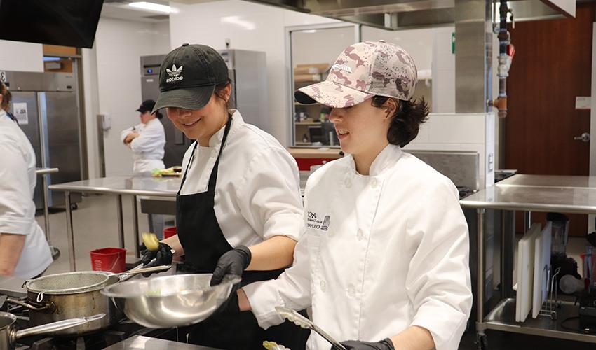 Two Culinary Art students having fun while they prepare  some dishes.